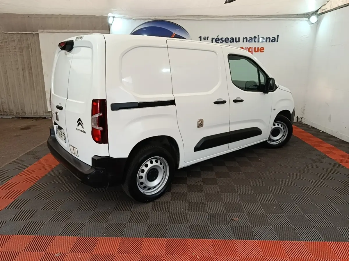 Vue 3/4 arrière droite d’un utilitaire Citroën Berlingo blanc avec protections latérales noires et jantes acier.