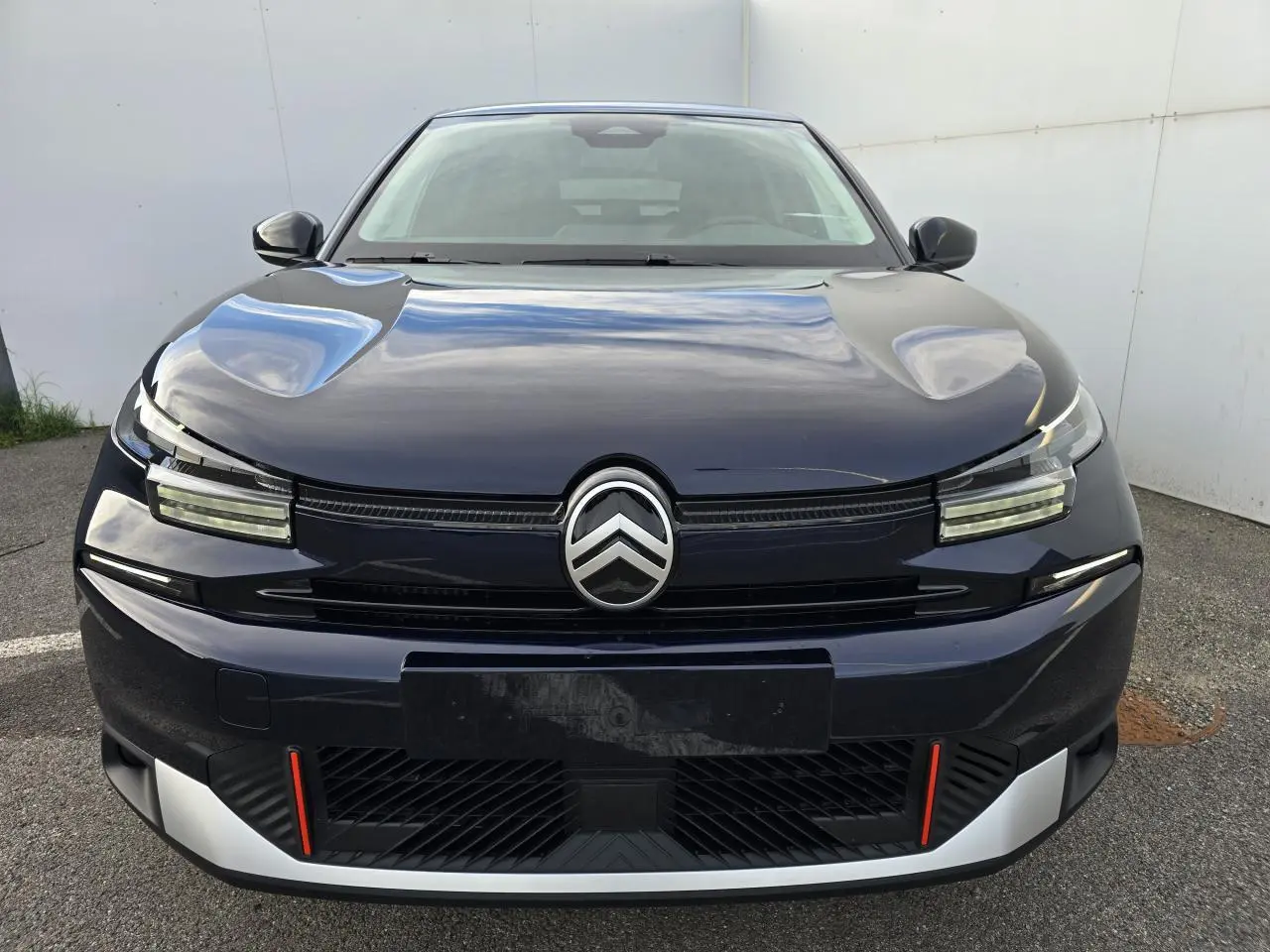 Vue frontale d'une Citroën C4 III hybride 2025 bleu eclipse avec toit noir et détails rouges sur le pare-chocs.