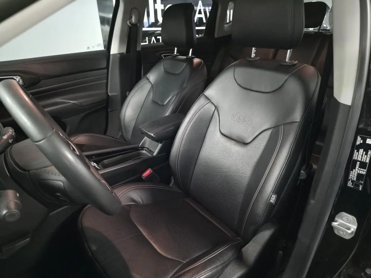 Vue intérieure côté conducteur du Jeep Compass 2022 avec sièges en cuir noir embossés du logo Jeep.