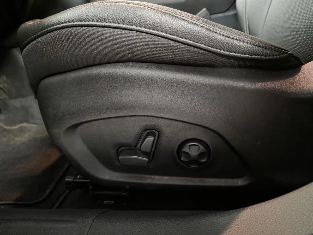 Réglage électrique du siège conducteur en cuir noir dans le Jeep Compass 2022, vue latérale rapprochée.