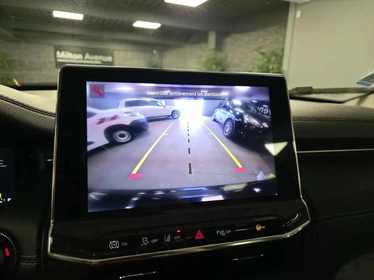 Écran tactile intérieur affichant la caméra de recul du Jeep Compass noir, vue arrière avec lignes de guidage jaunes.