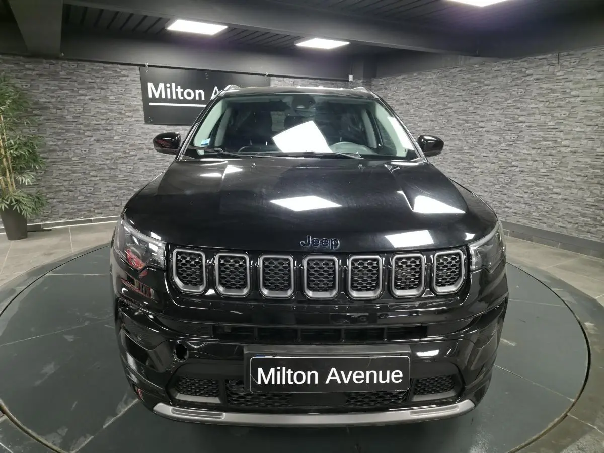 Vue frontale d'un Jeep Compass noir brillant avec calandre à sept fentes et plaque Milton Avenue.
