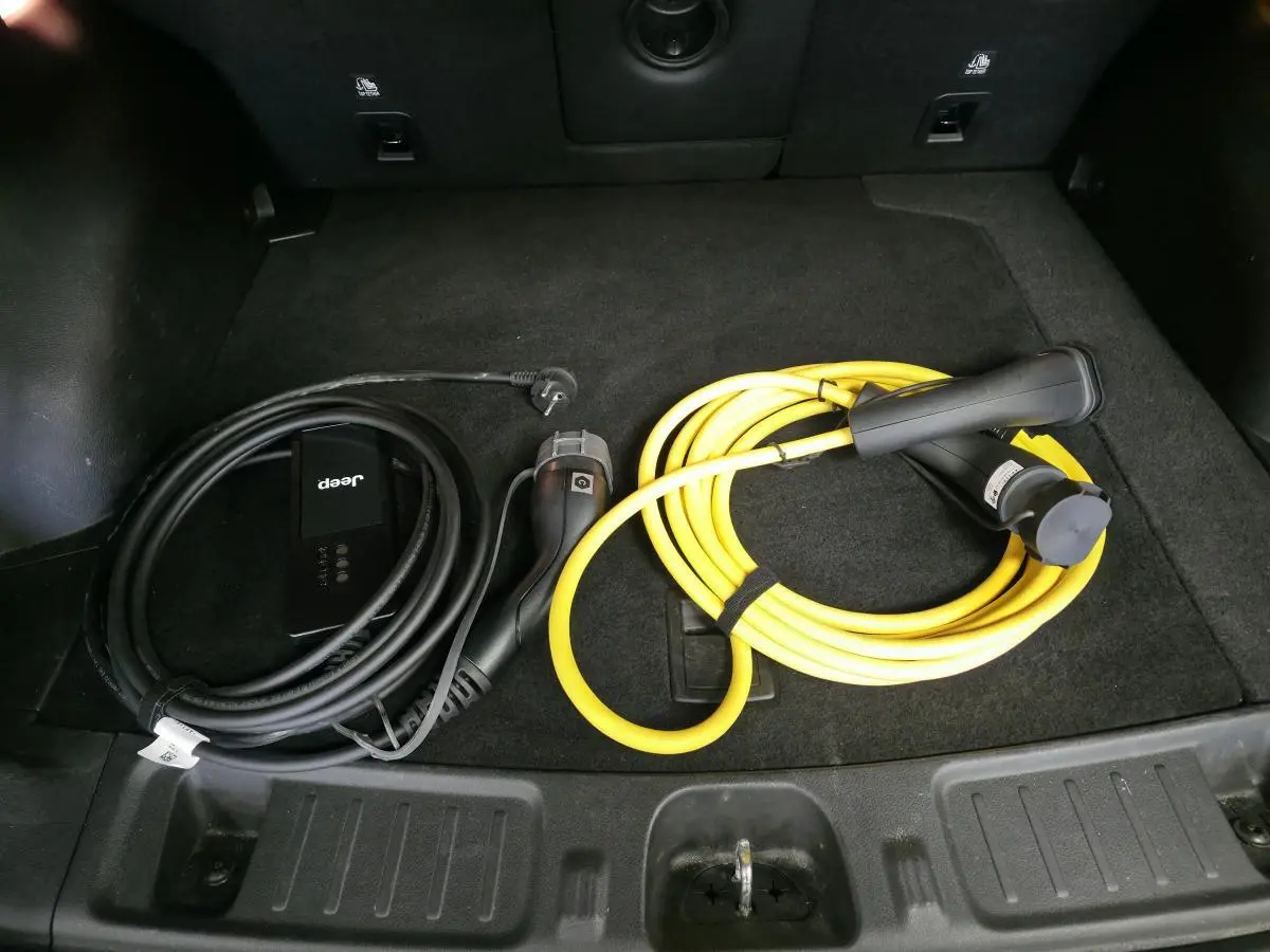 Vue du coffre noir du Jeep Compass 2022 avec câbles de recharge type 2 noir et jaune pour hybride rechargeable.