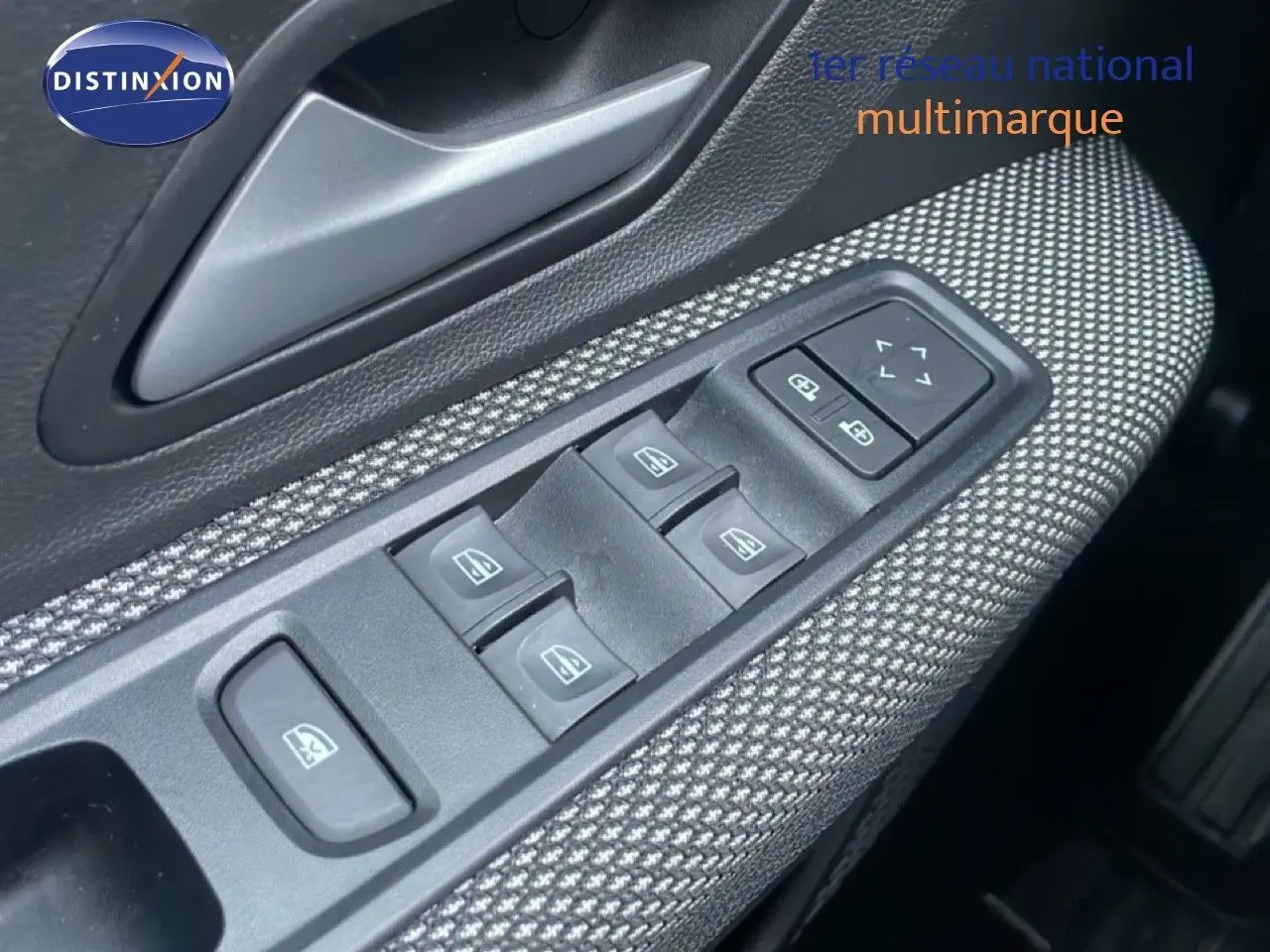 Gros plan sur la commande des vitres électriques côté conducteur avec habillage tissu gris dans un Dacia Jogger vert cèdre métal.