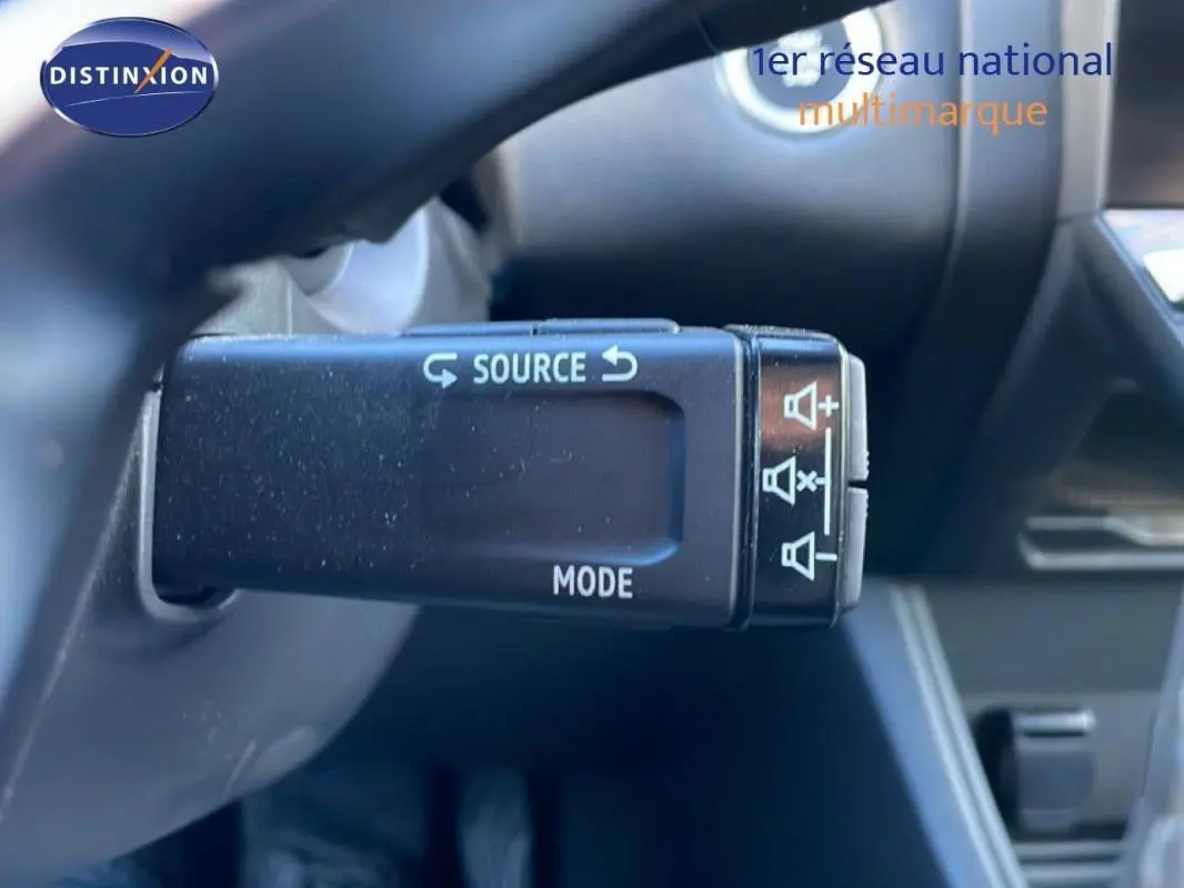 Gros plan sur la commande au volant du Renault Captur rouge 2025, mettant en valeur les boutons source et mode.