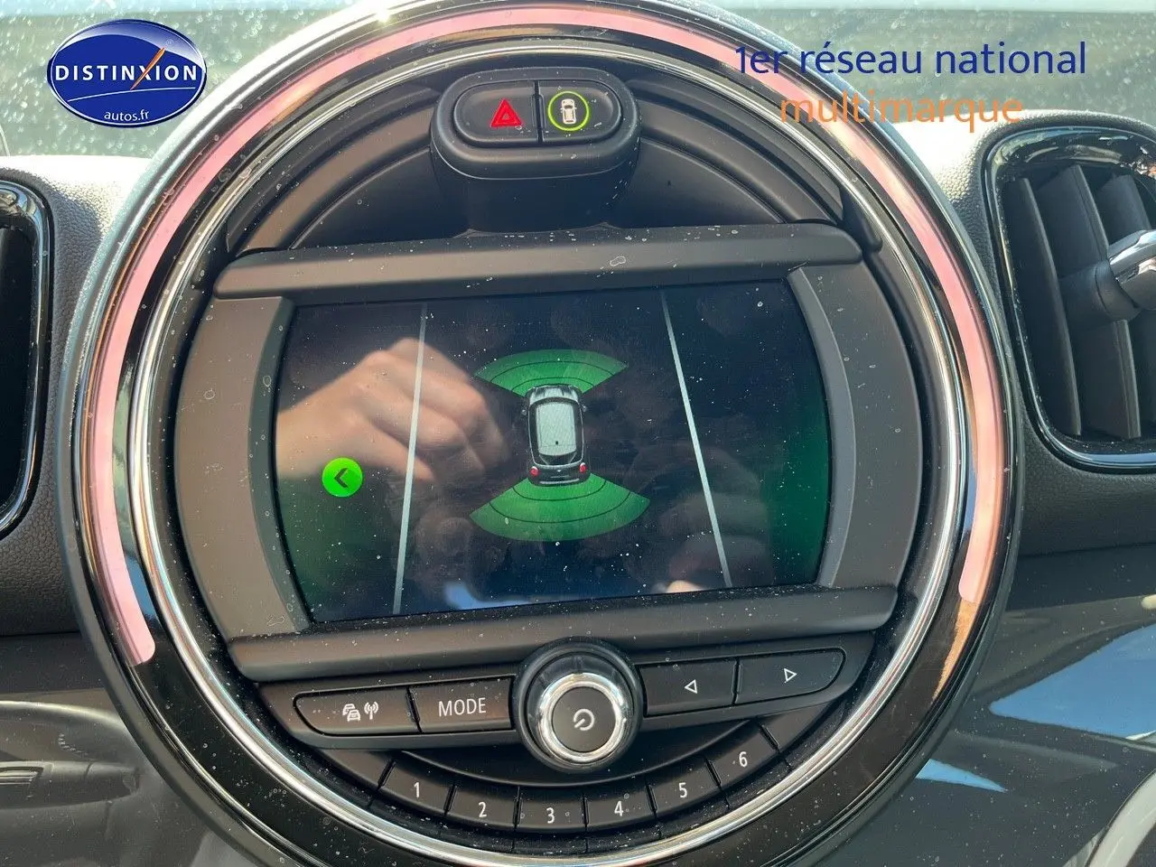 Écran central du MINI Countryman Cooper SE 2019 montrant l'assistance au stationnement, entouré de commandes circulaires.