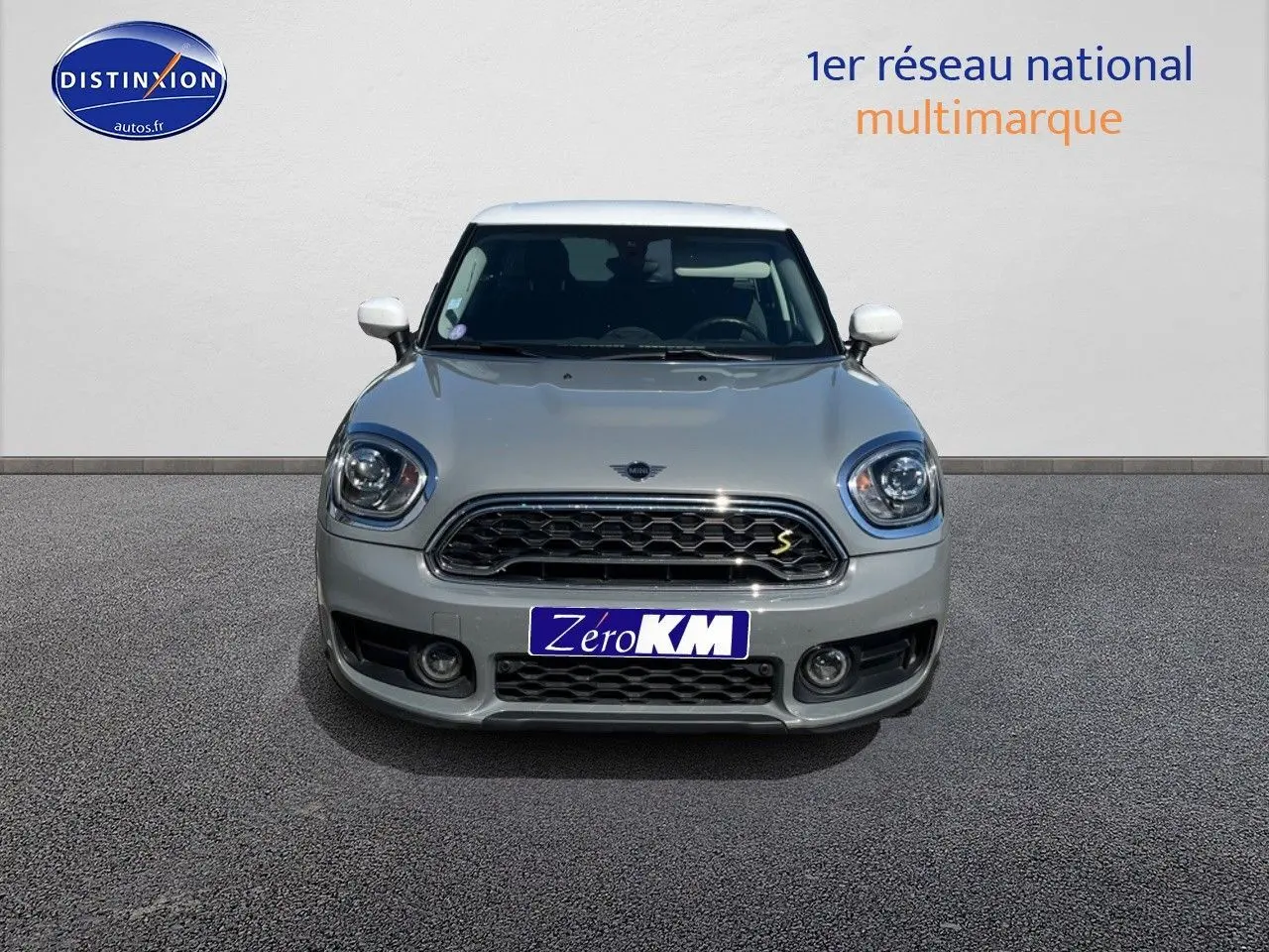 Vue frontale d'une MINI Countryman Cooper SE Moonwalk Grey avec toit et rétroviseurs blancs, calandre chromée.