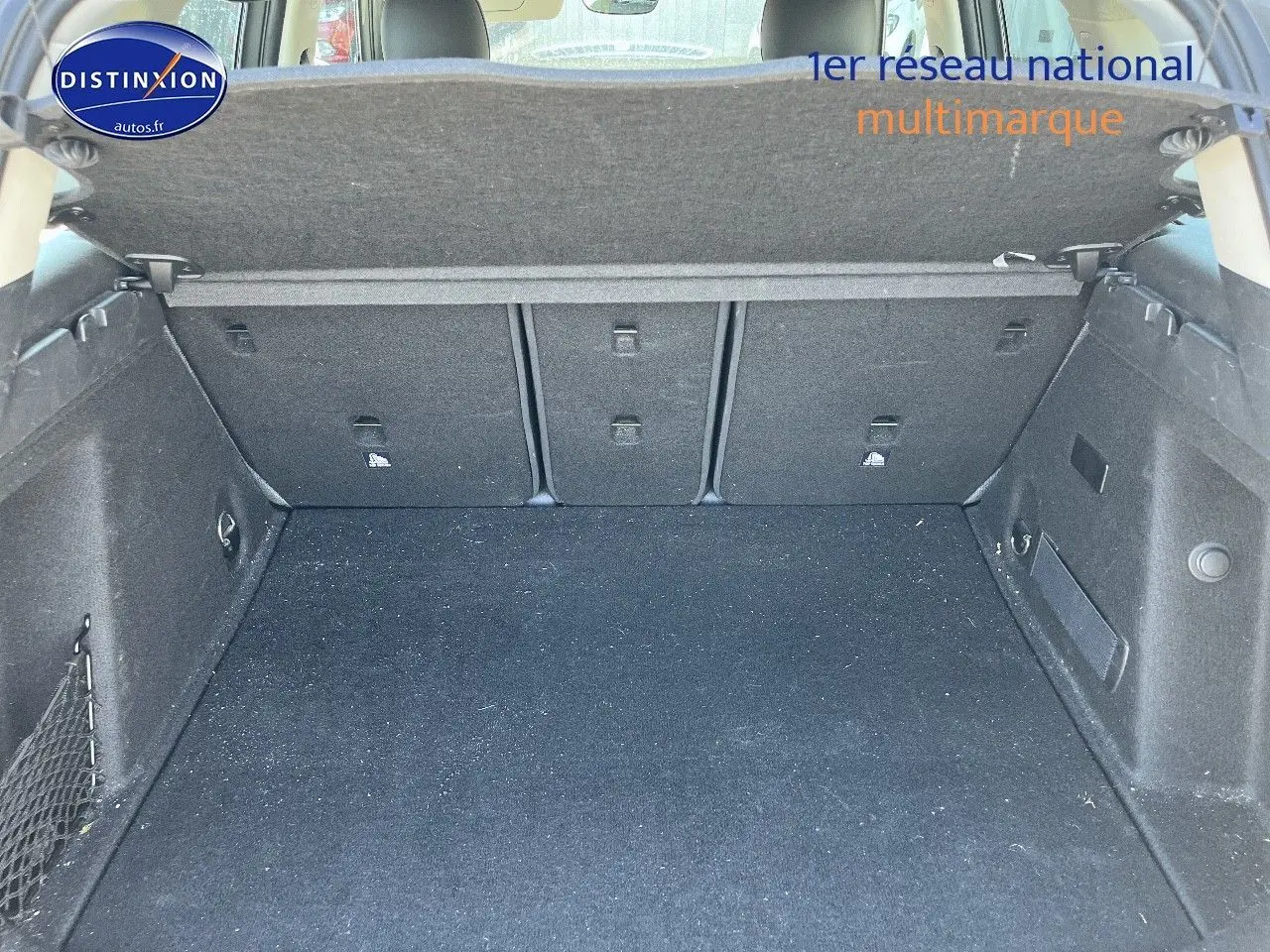 Coffre ouvert vu de face d’un MINI Countryman hybride gris Moonwalk avec cache-bagages relevé.