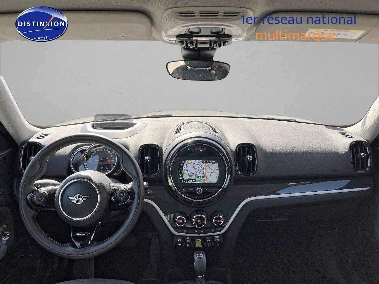 Vue intérieure frontale du tableau de bord noir du MINI Countryman Cooper SE avec écran GPS circulaire et volant multifonction.