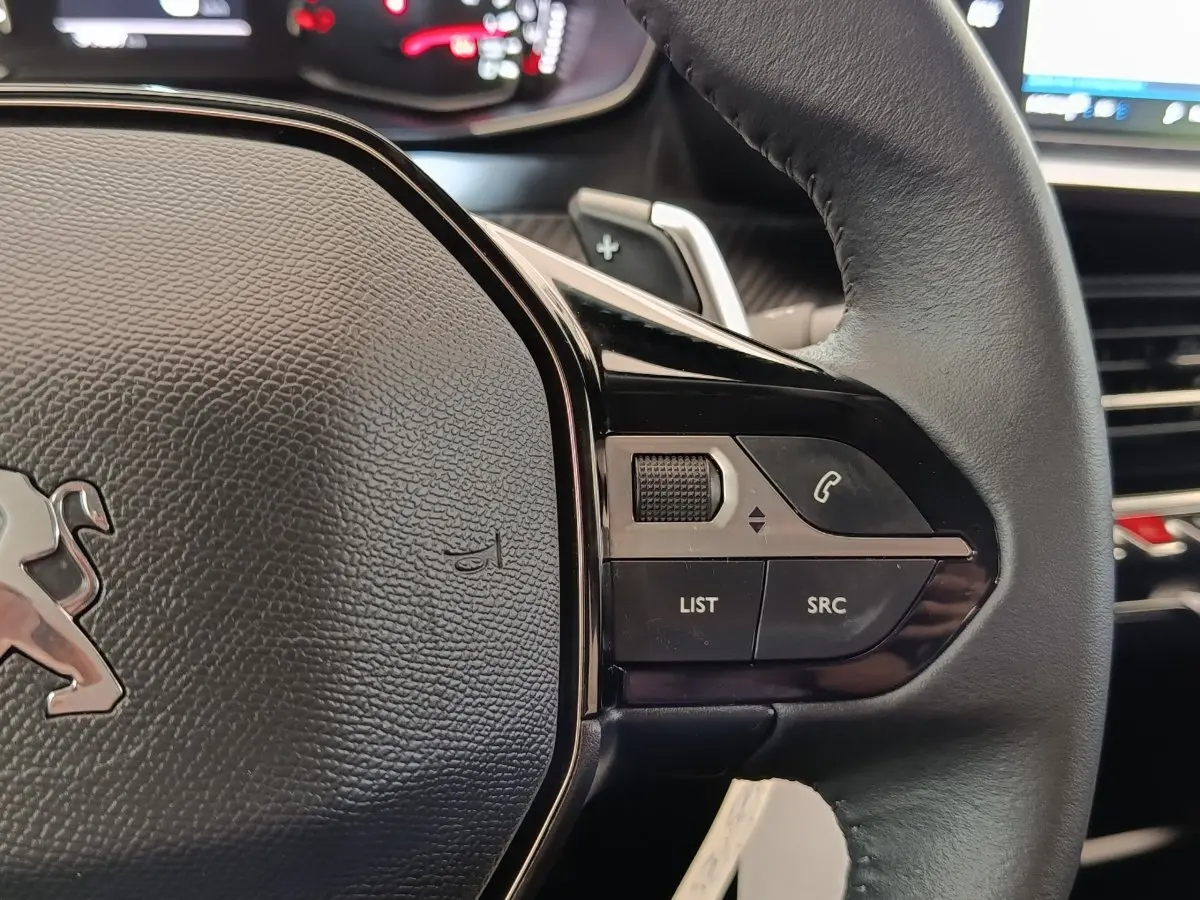 Gros plan sur le volant cuir multifonctions noir du Peugeot 2008, avec commandes audio et téléphone intégrées.