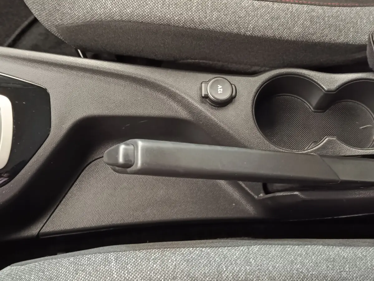 Vue rapprochée de la console centrale noire avec frein à main manuel et prise 12V du Peugeot 2008 blanc.