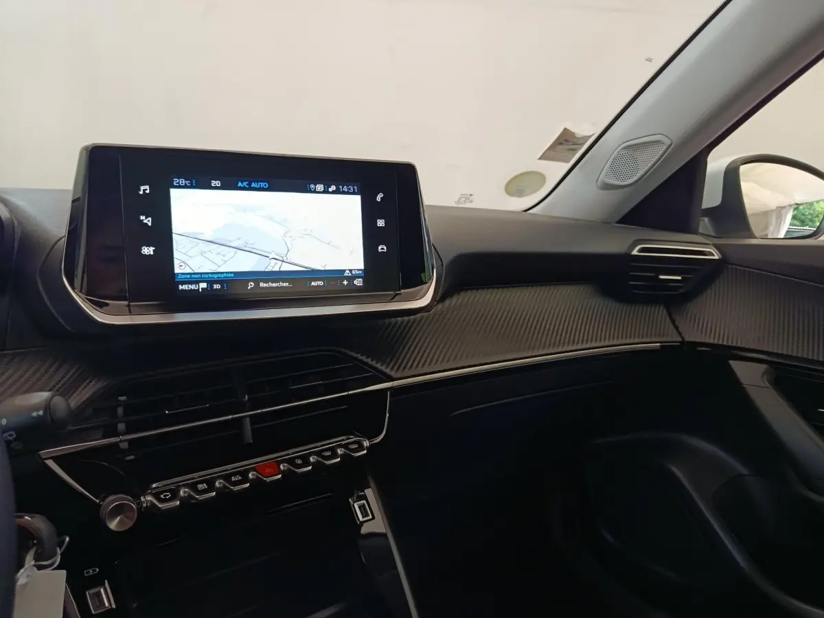 Tableau de bord intérieur du Peugeot 2008 blanc 2021, vue côté passager avec écran tactile de navigation allumé.