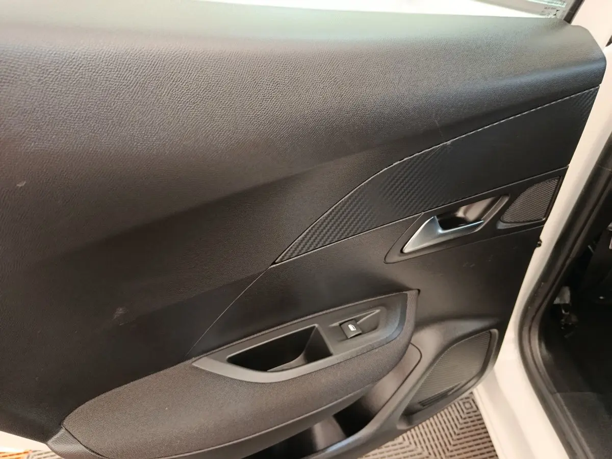 Vue intérieure de la porte avant droite noire du Peugeot 2008 blanc, avec poignée argentée et bouton de lève-vitre.