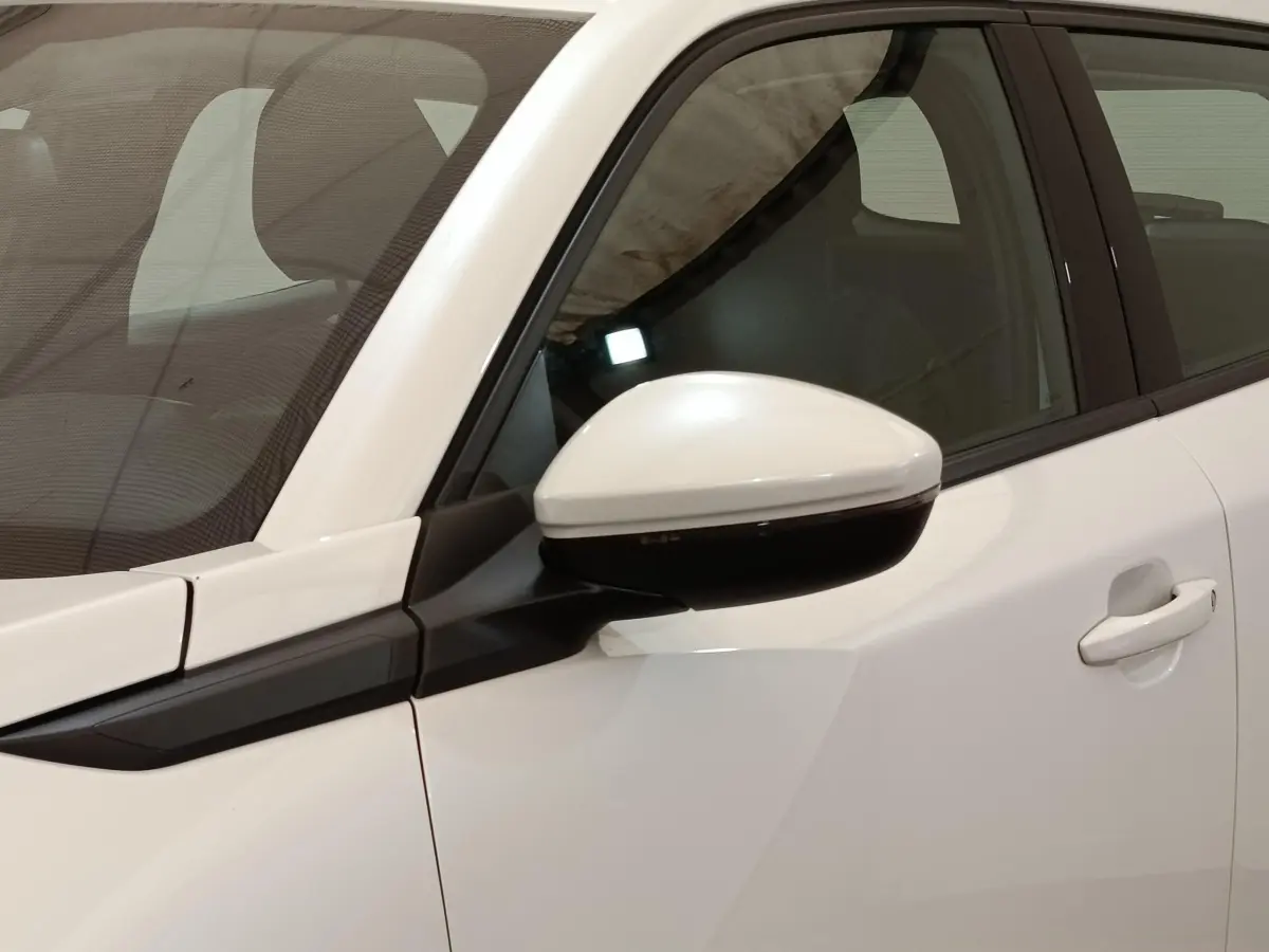 Vue rapprochée du rétroviseur côté conducteur blanc et noir du Peugeot 2008 blanc, avec porte et vitre arrière visibles.