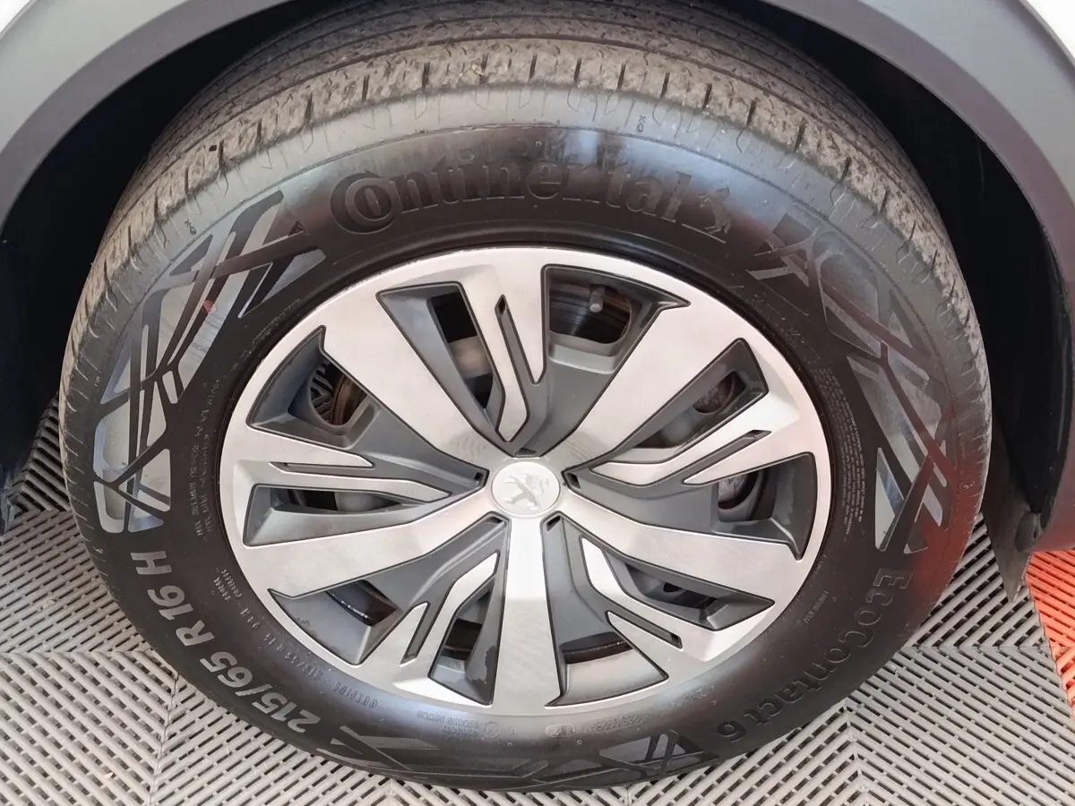 Gros plan sur la roue avant droite d'une Peugeot 2008 blanche, jante alliage au design moderne et pneu Continental.