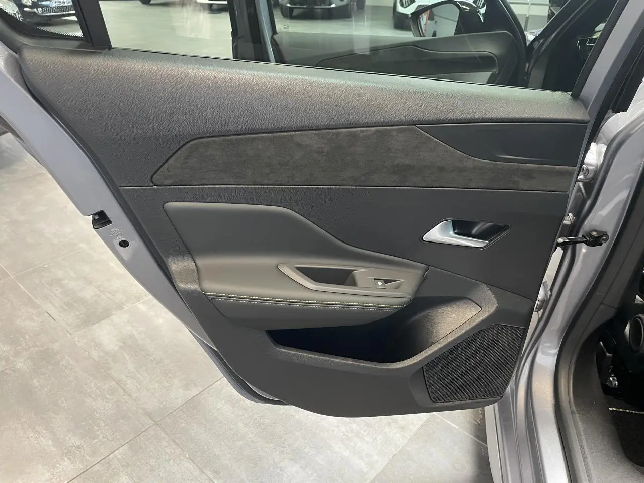 Vue côté gauche de la porte arrière ouverte d’une Peugeot 308 gris Artense avec habillage noir et surpiqûres vert Adamite.