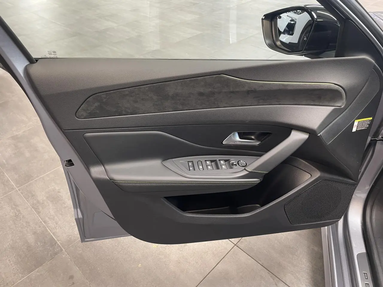 Vue intérieure de la porte avant gauche gris Artense avec surpiqûres vert Adamite et insert Alcantara sur Peugeot 308 2026.