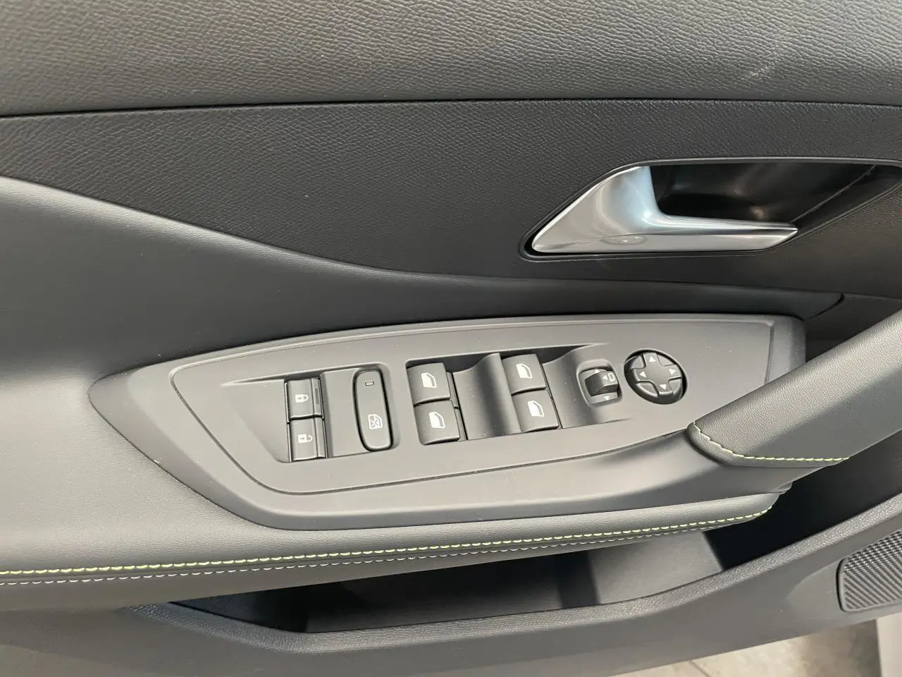 Détail de la porte avant gauche du Peugeot 308 gris Artense avec commandes des vitres et surpiqûres vert Adamite.
