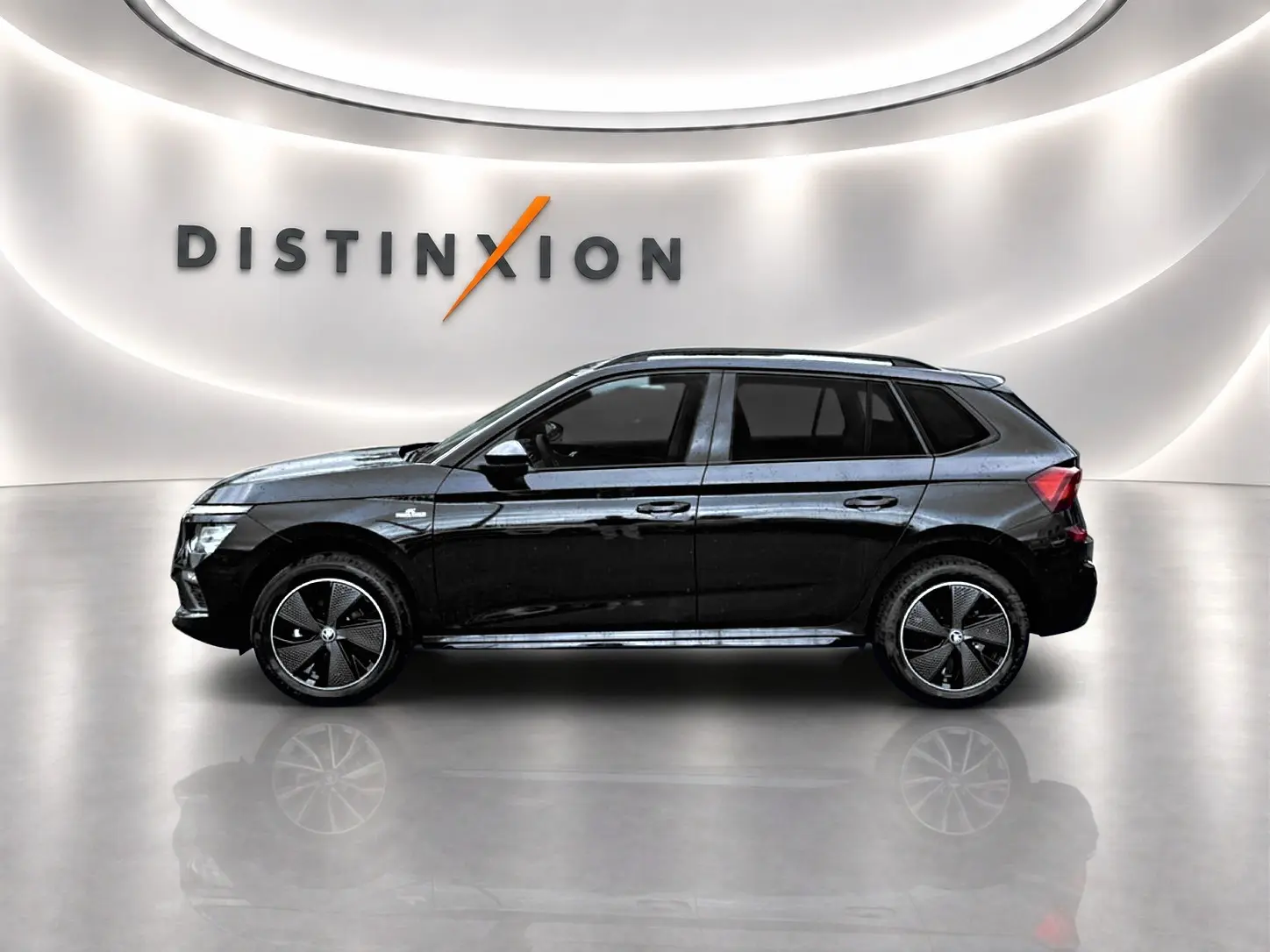 Vue de profil côté gauche d’un Skoda Kamiq noir 2026 finition Monte Carlo dans un showroom lumineux.