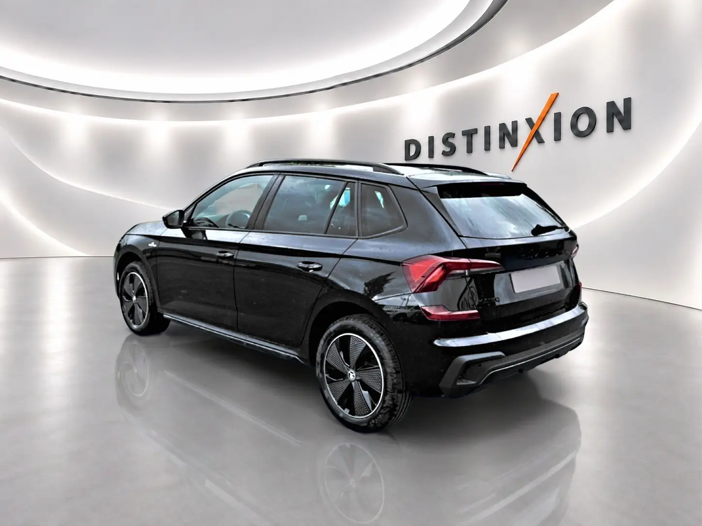 Vue 3/4 arrière droite d'un Skoda Kamiq noir avec jantes alu et toit panoramique en showroom lumineux.