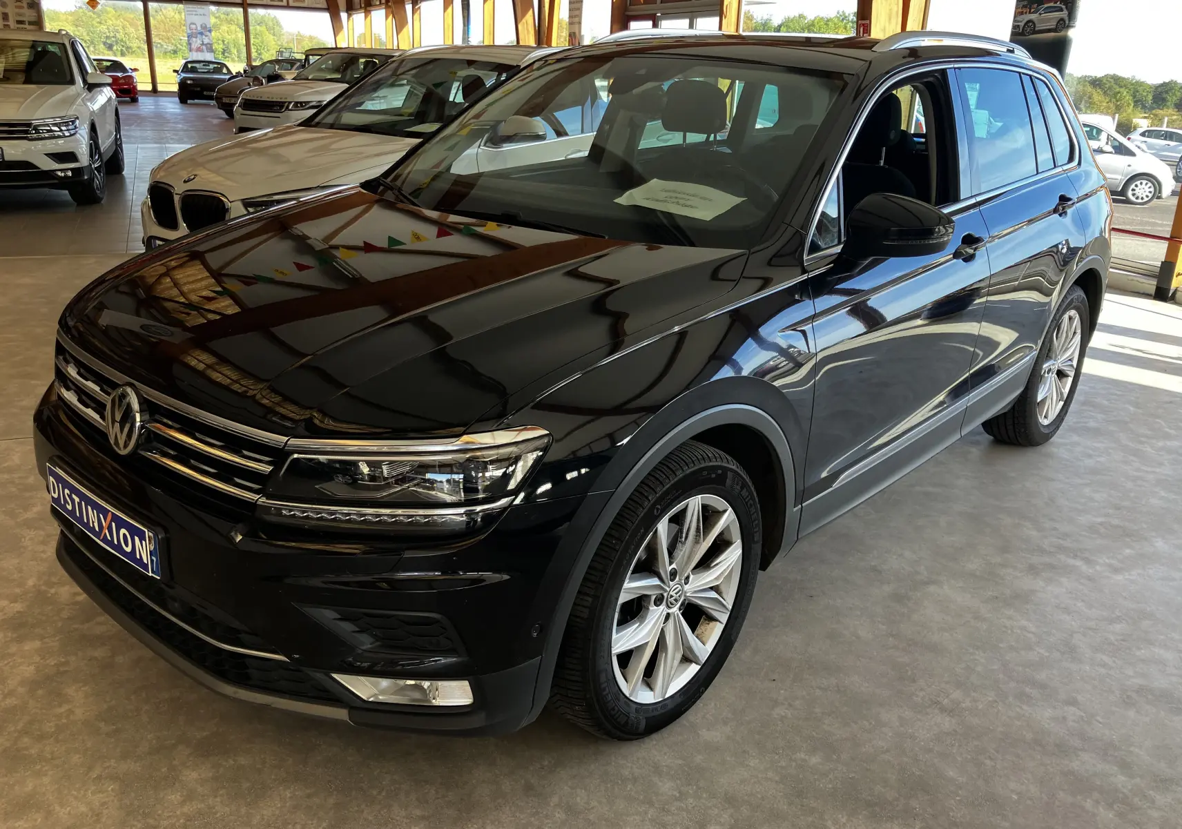 Volkswagen Tiguan noir en 3/4 avant droit dans un showroom, avec jantes alliage et calandre chromée visible.