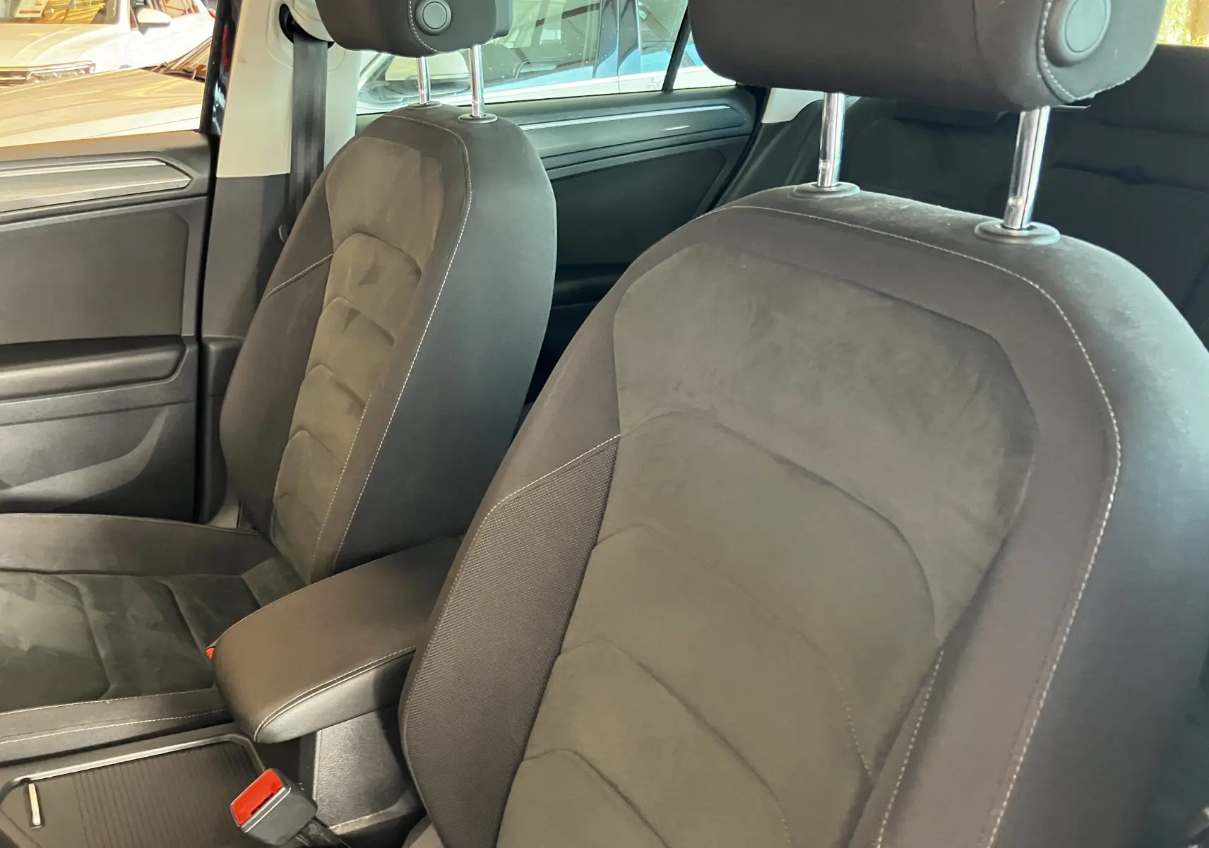 Gros plan sur les sièges avant en tissu noir du Volkswagen Tiguan 2017, avec accoudoir central visible.