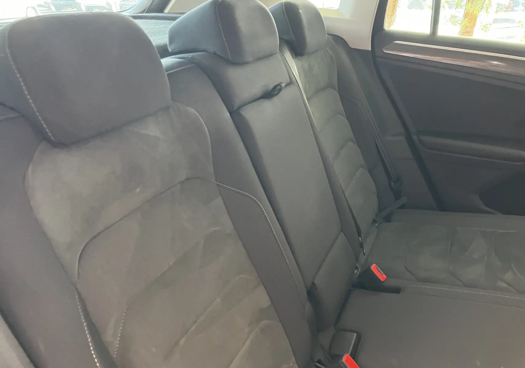 Vue intérieure du siège arrière noir en tissu et alcantara du Volkswagen Tiguan 2017, avec appuie-têtes et ceintures visibles.