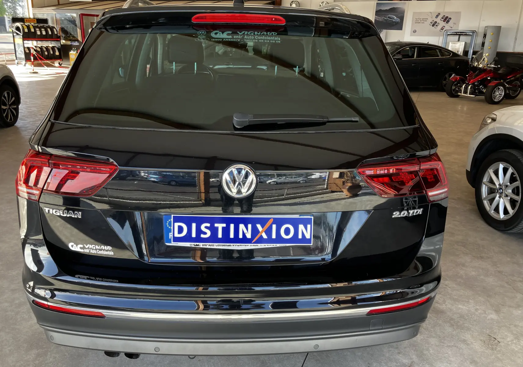 Vue arrière d'un Volkswagen Tiguan noir 2,0L TDI 150 DSG Carat avec feux rouges et logo distinctif sur hayon.