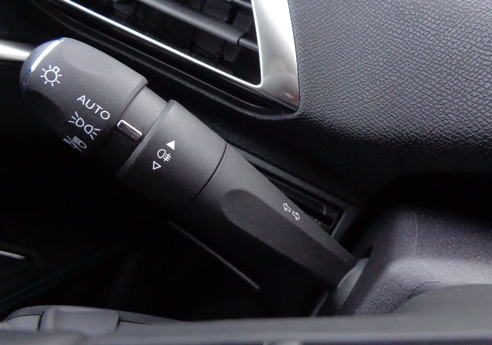 Gros plan sur la commande des phares et clignotants dans l'habitacle noir du Peugeot 5008 gris platinium 2023.