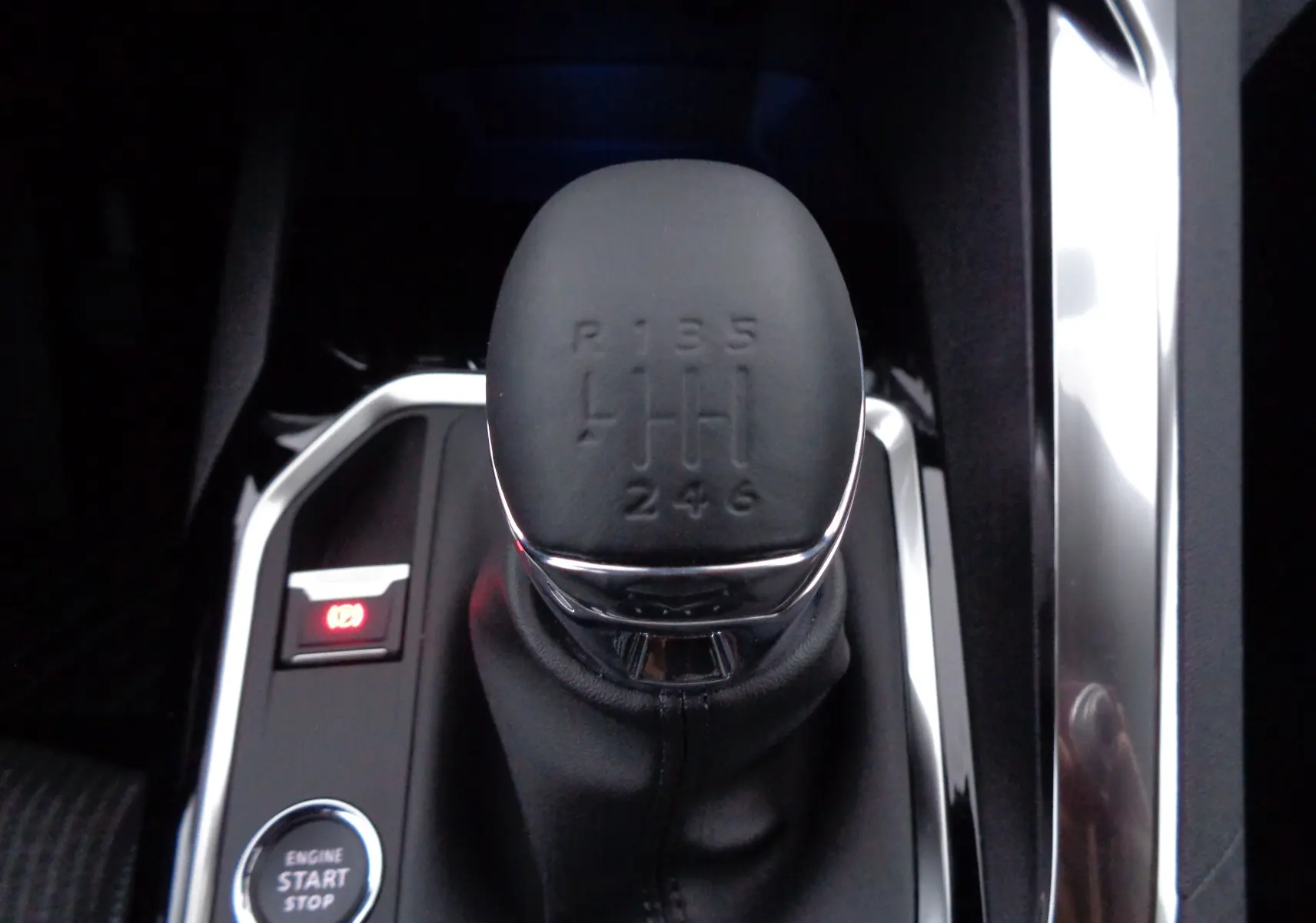 Gros plan sur le levier de vitesses manuel noir du Peugeot 5008 gris platinium, avec bouton start/stop à côté.