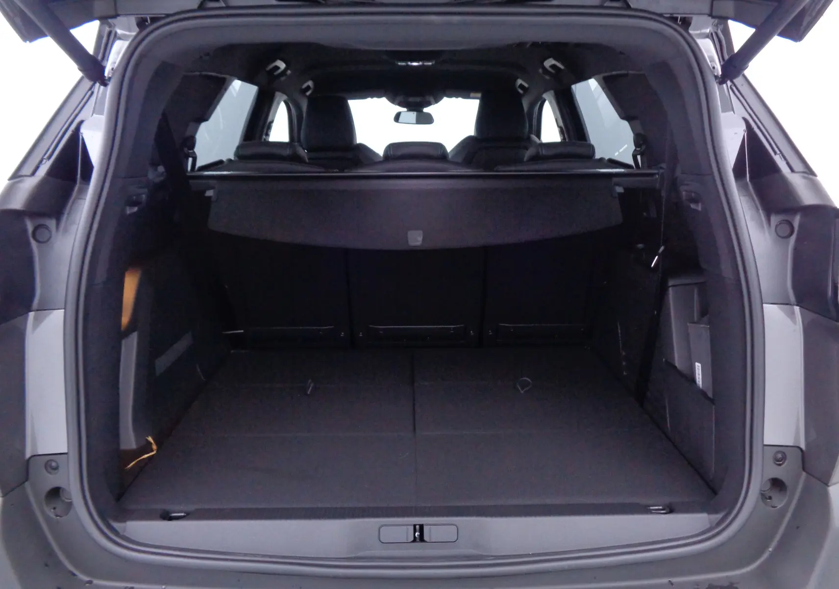 Coffre ouvert vu de l'arrière d'un Peugeot 5008 gris platinium métal, montrant un espace de chargement spacieux et modulable.