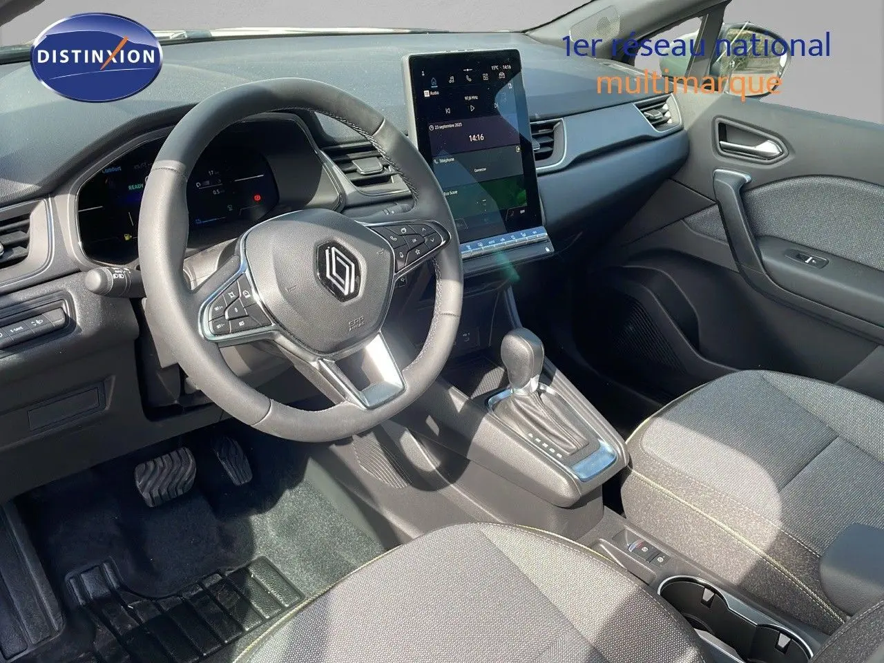Intérieur du Renault Captur 2025 en tissu gris, vue côté conducteur sur volant, écran tactile et levier de boîte auto.