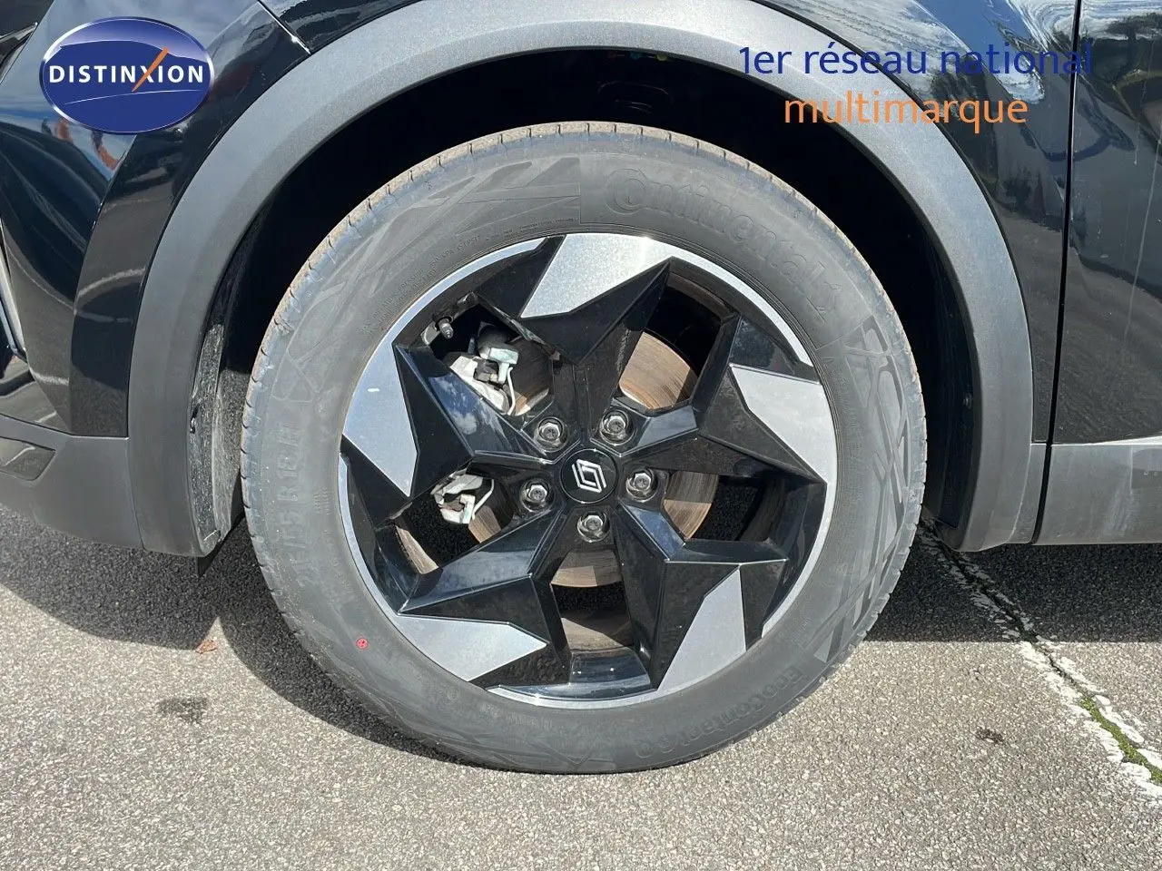 Gros plan sur la roue avant gauche du Renault Captur noir étoile métal avec jante noire et grise au design géométrique.