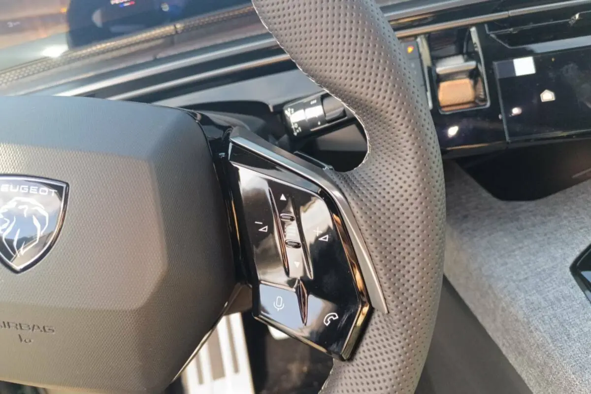 Gros plan sur le volant cuir perforé côté droit du Peugeot 3008 Hybrid 145 GT avec commandes multifonctions.