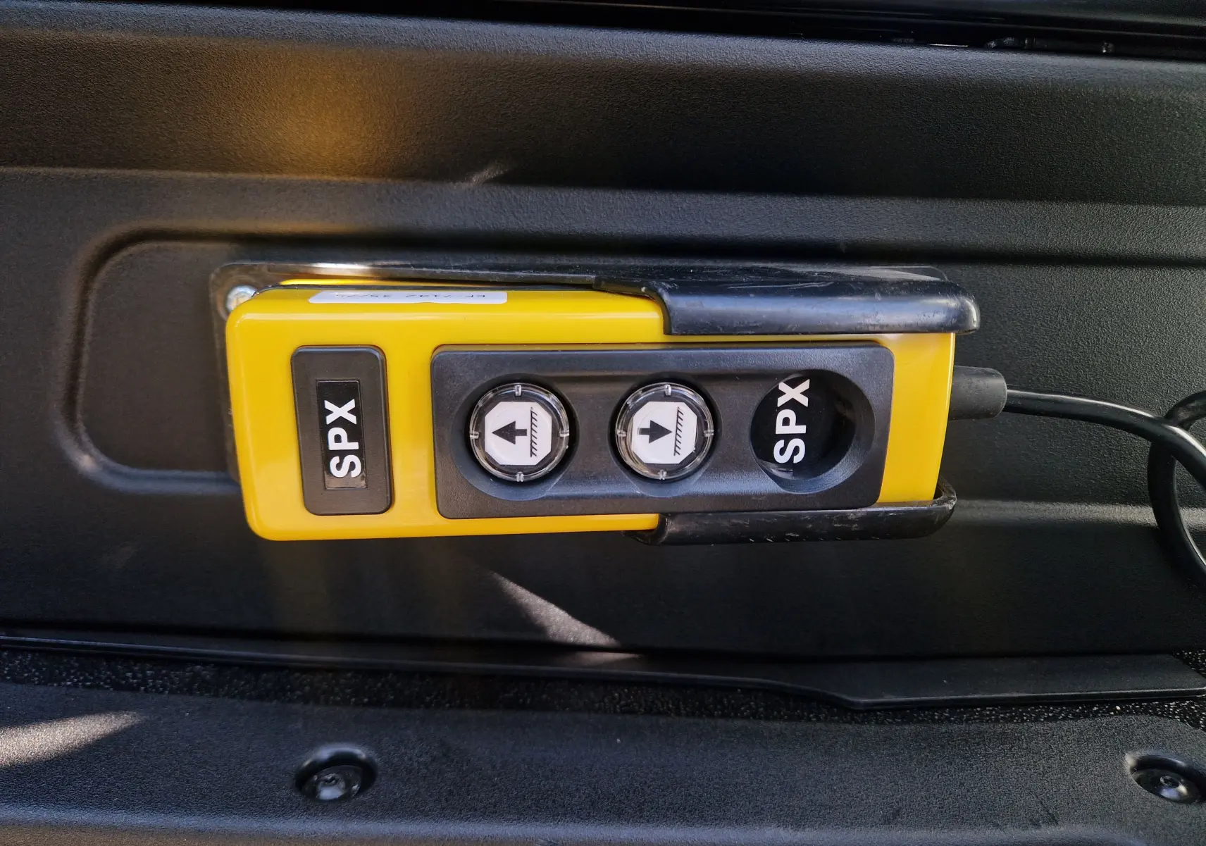 Gros plan sur la commande jaune SPX avec deux boutons fléchés dans l'habitacle d'un Iveco Daily blanc.