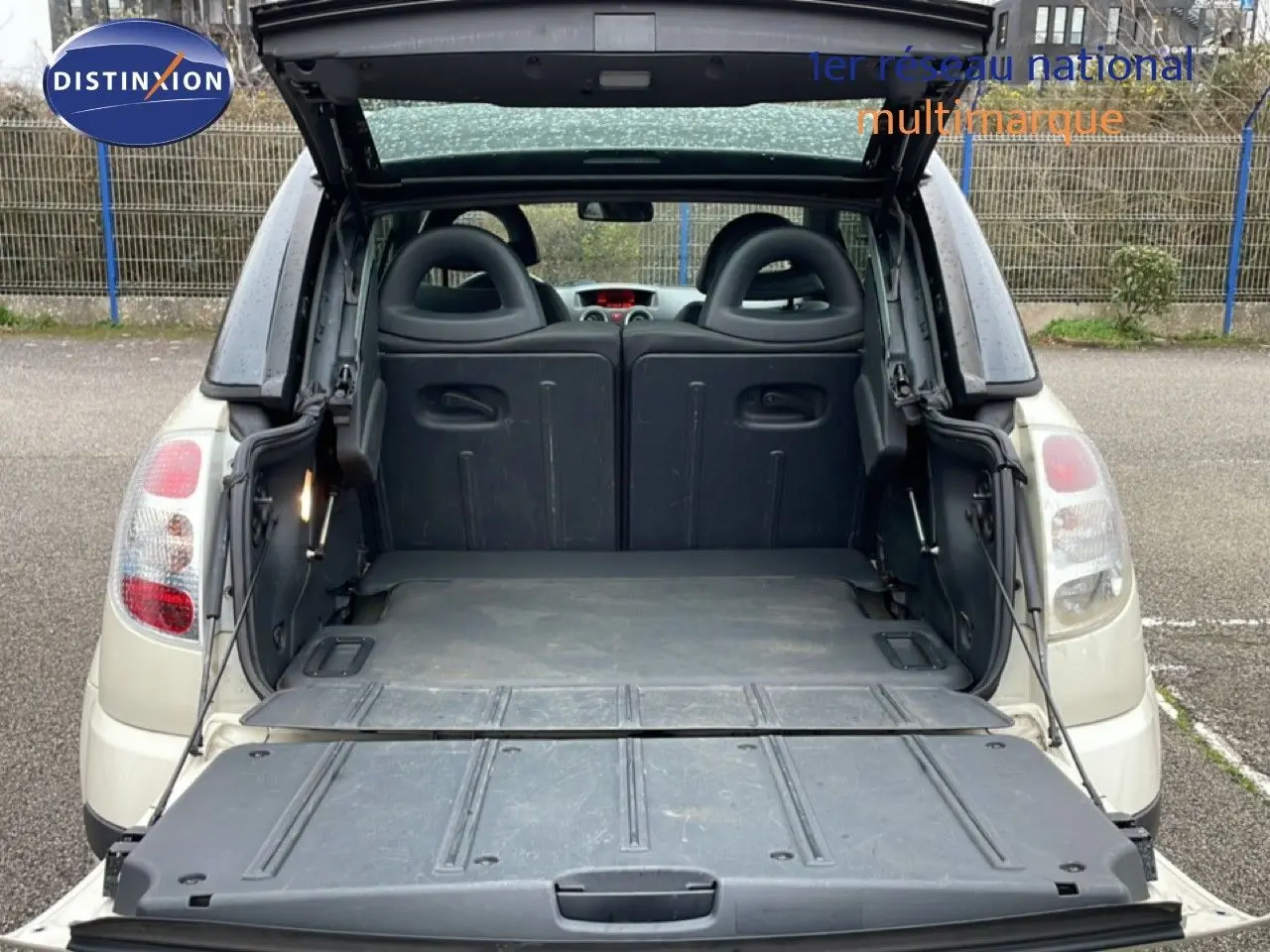 Vue arrière ouverte d'une Citroën C3 Pluriel ivoire de 2007, montrant le coffre et les dossiers de sièges rabattus.