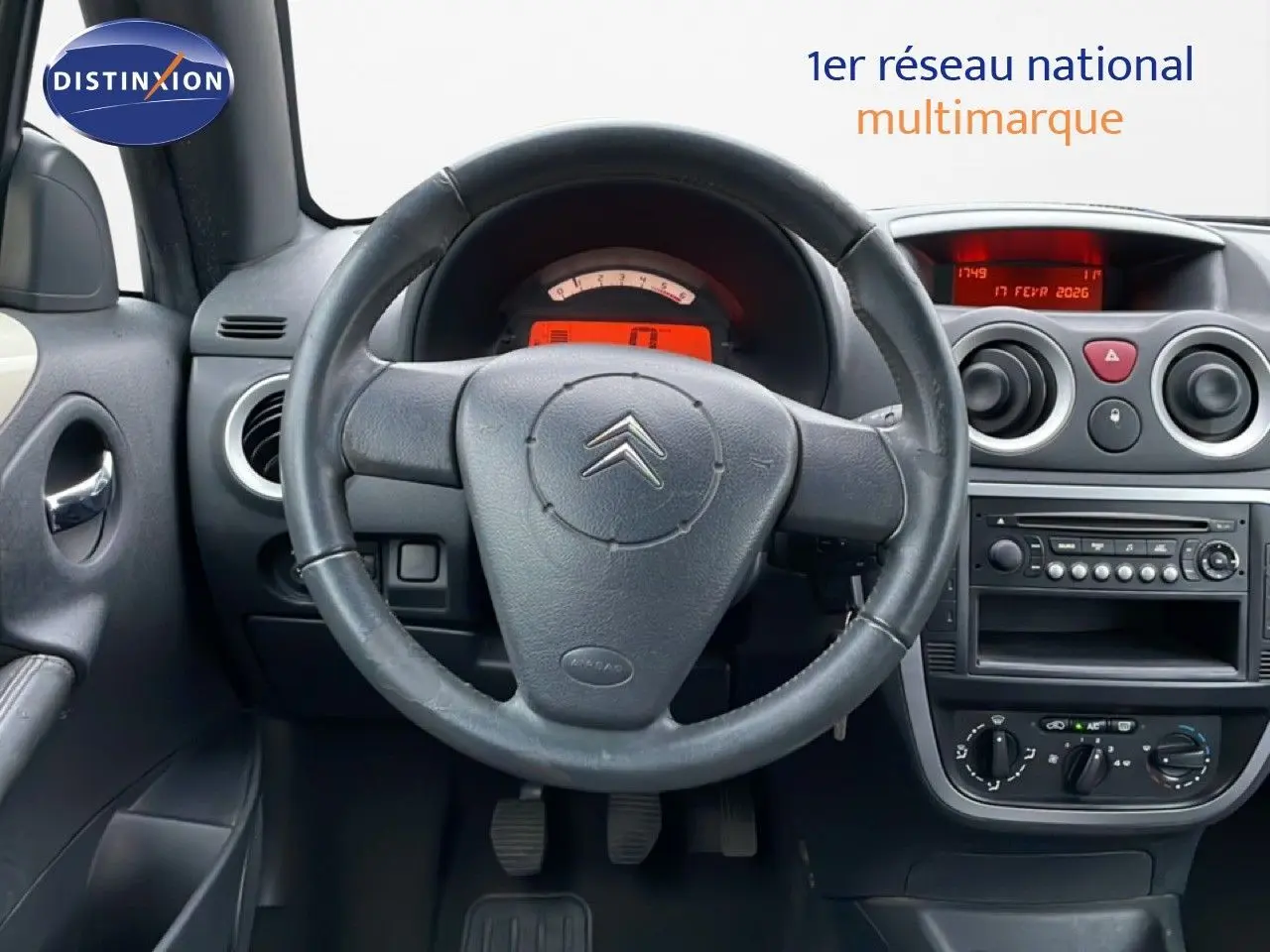 Intérieur de Citroën C3 Pluriel ivoire 2007, vue frontale du tableau de bord avec volant cuir et console centrale.