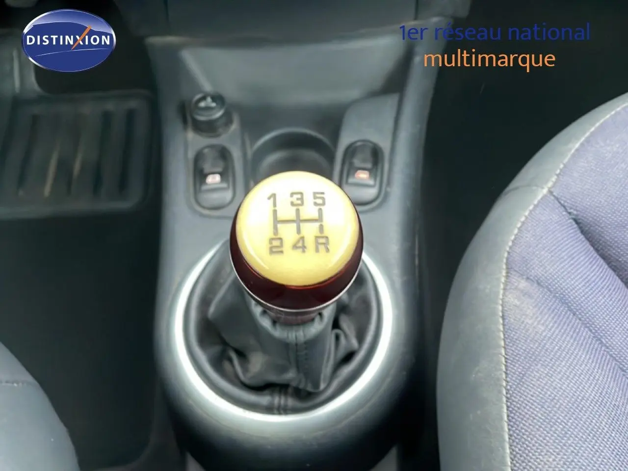 Le levier de vitesses manuel ivoire et marron de la Citroën C3 Pluriel 2007 vu de dessus, avec sièges tissu noir-beige.