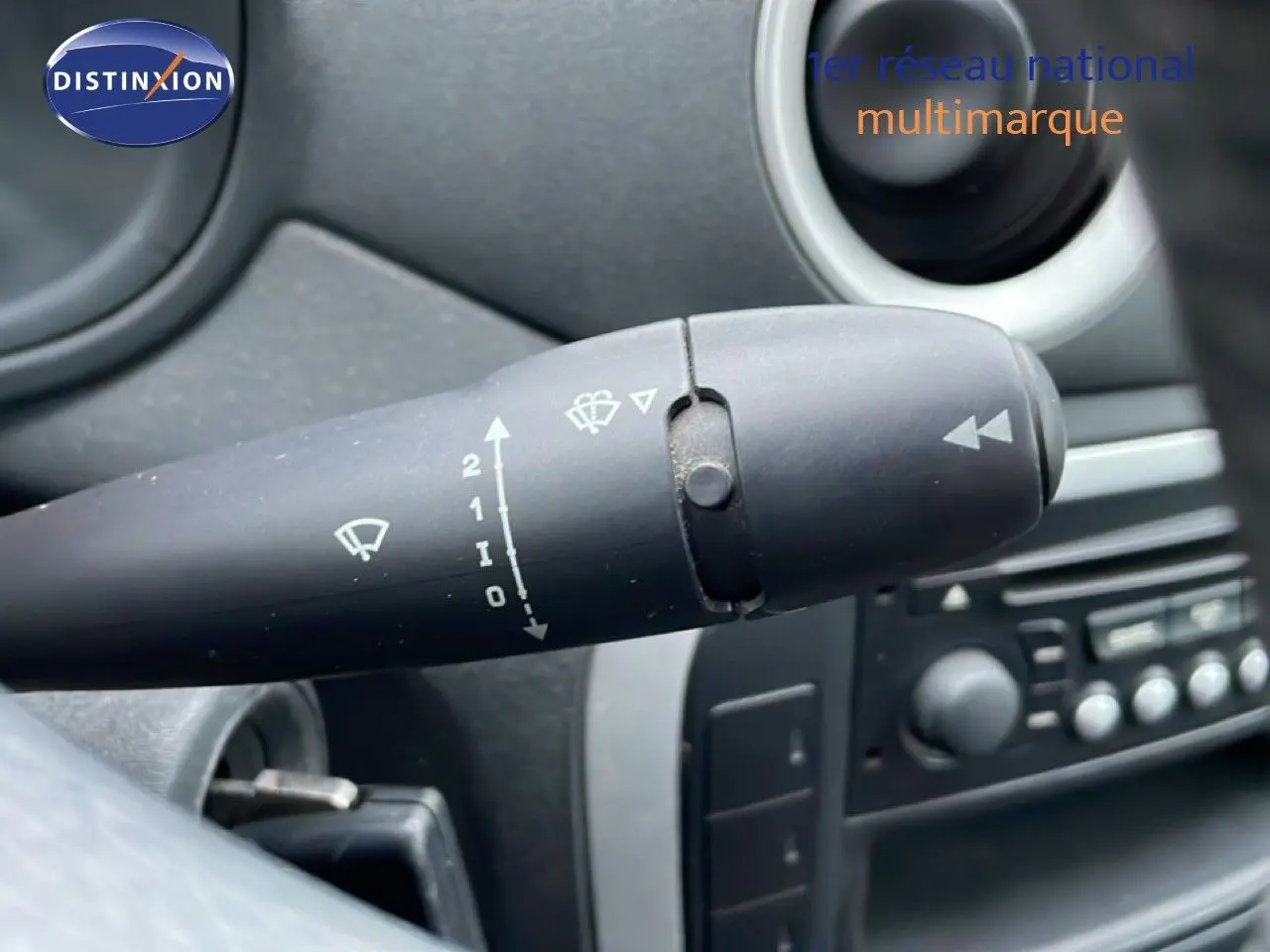 Gros plan sur la commande d’essuie-glace à gauche du volant dans l’habitacle noir et beige d’une Citroën C3 Pluriel ivoire.