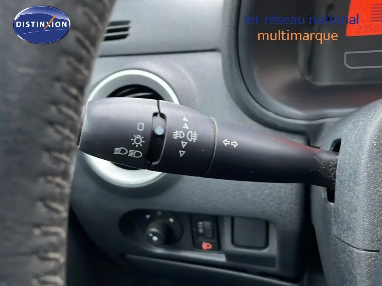 Gros plan sur la commande de clignotant à gauche du volant d’une Citroën C3 Pluriel ivoire de 2007.