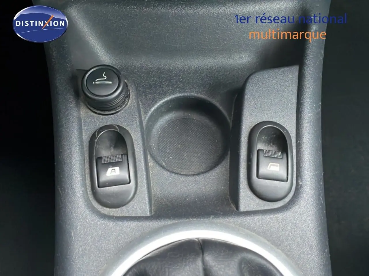 Gros plan sur la console centrale noire de la Citroën C3 Pluriel 2007, montrant les commandes des vitres électriques.