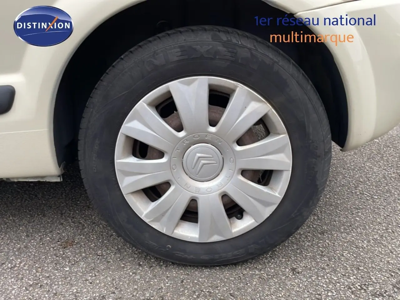 Gros plan sur la roue avant gauche ivoire d'une Citroën C3 Pluriel 1.4 HDI 70ch avec enjoliveur d'origine.