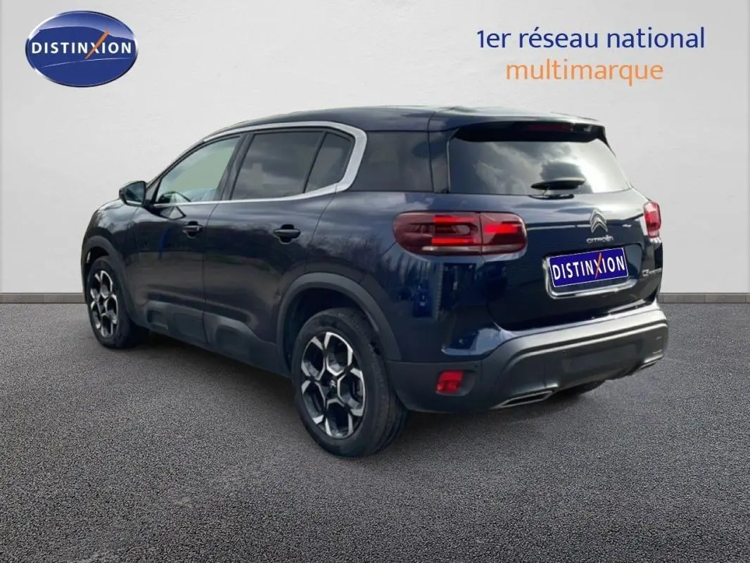 Vue 3/4 arrière droite d'un Citroën C5 Aircross bleu 2024 avec jantes aluminium et feux arrière allumés.