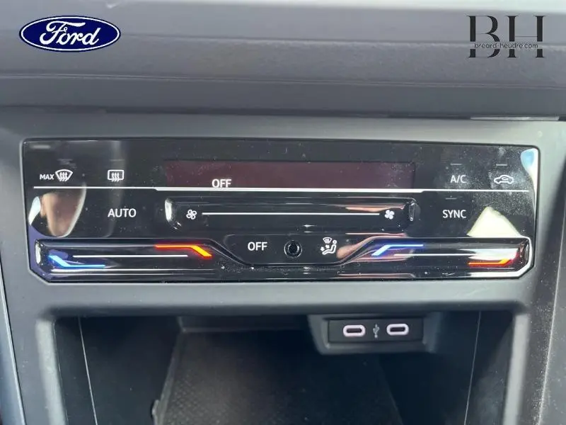 Détail du panneau de commande de climatisation avec réglages tactiles et éclairage bleu et rouge sur Volkswagen Polo argentée.