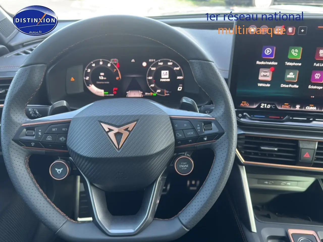 Vue intérieure centrée sur le volant sport en cuir noir avec logo CUPRA et écran tactile multifonction à droite.