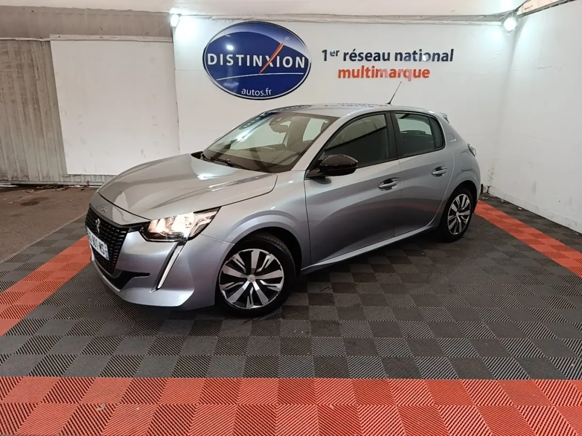 Peugeot 208 gris clair vue 3/4 avant droit, avec feux LED allumés et rétroviseurs noirs contrastants.