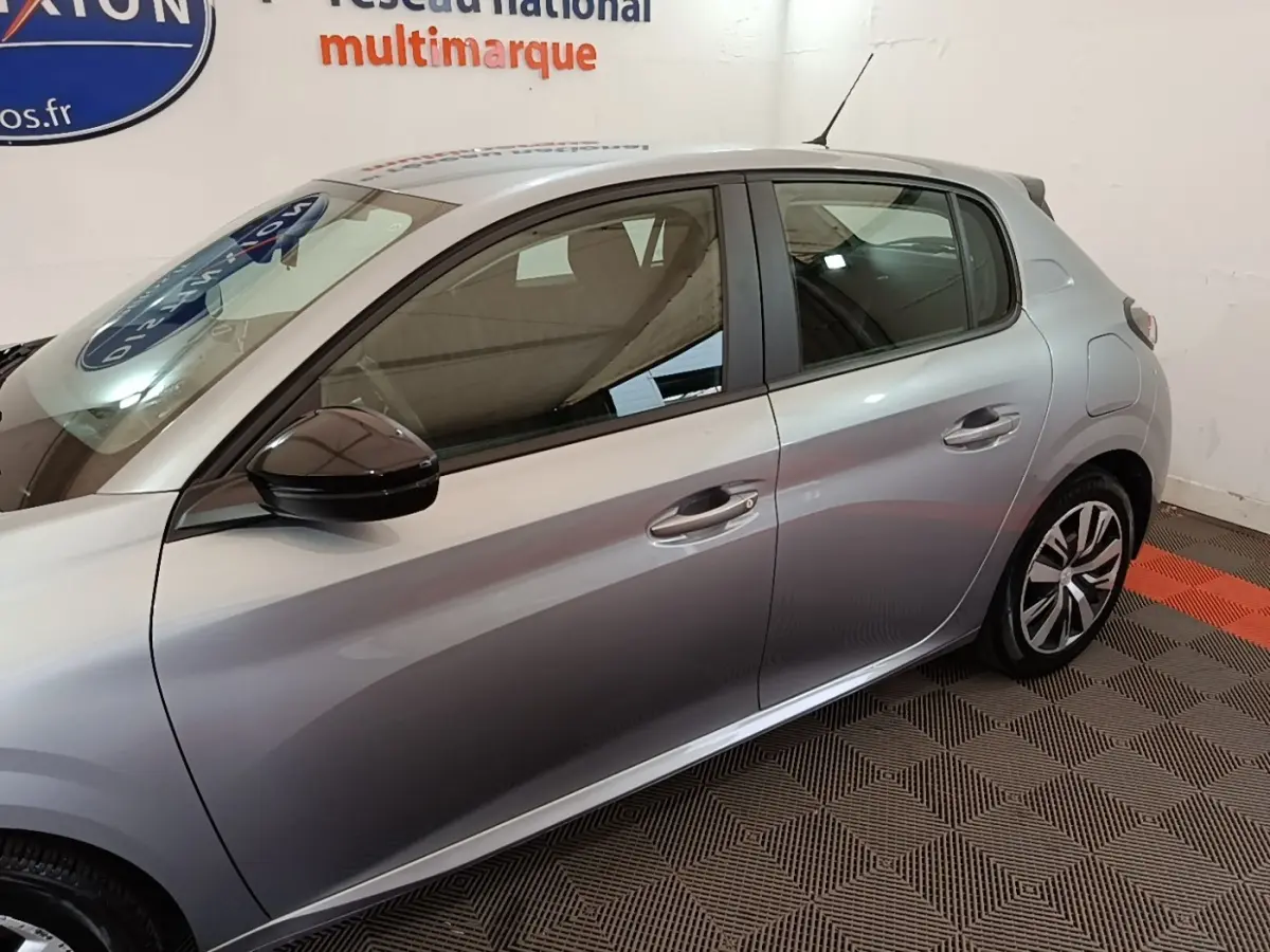 Profil droit de la Peugeot 208 gris clair 2023, mettant en valeur les jantes et les rétroviseurs noirs.