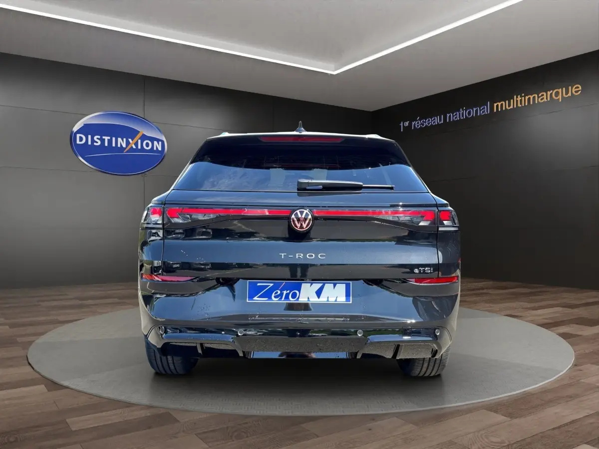 Vue arrière du Volkswagen T-Roc noir 2026 avec feux LED traversants et badge eTSI visible sur fond showroom.