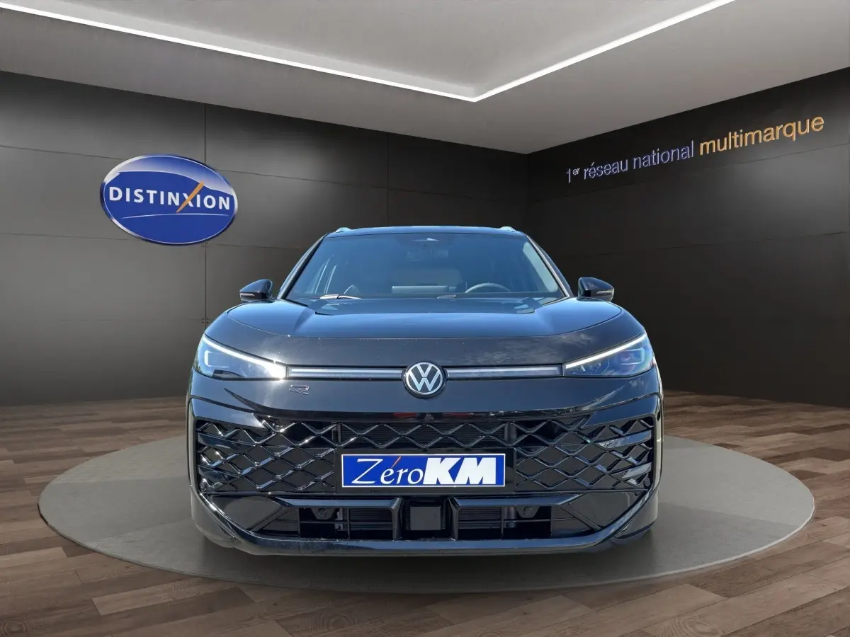 Vue frontale d'un Volkswagen T-Roc noir 2026 avec calandre large et phares LED fins allumés en showroom.