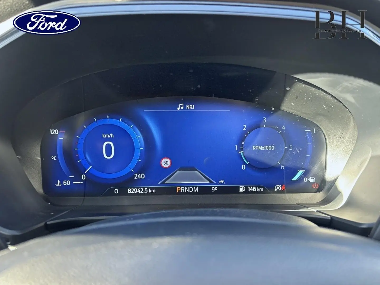 Vue rapprochée du tableau de bord numérique bleu du Ford Kuga 1.5 EcoBlue 2021, affichant vitesse, compte-tours et informations.